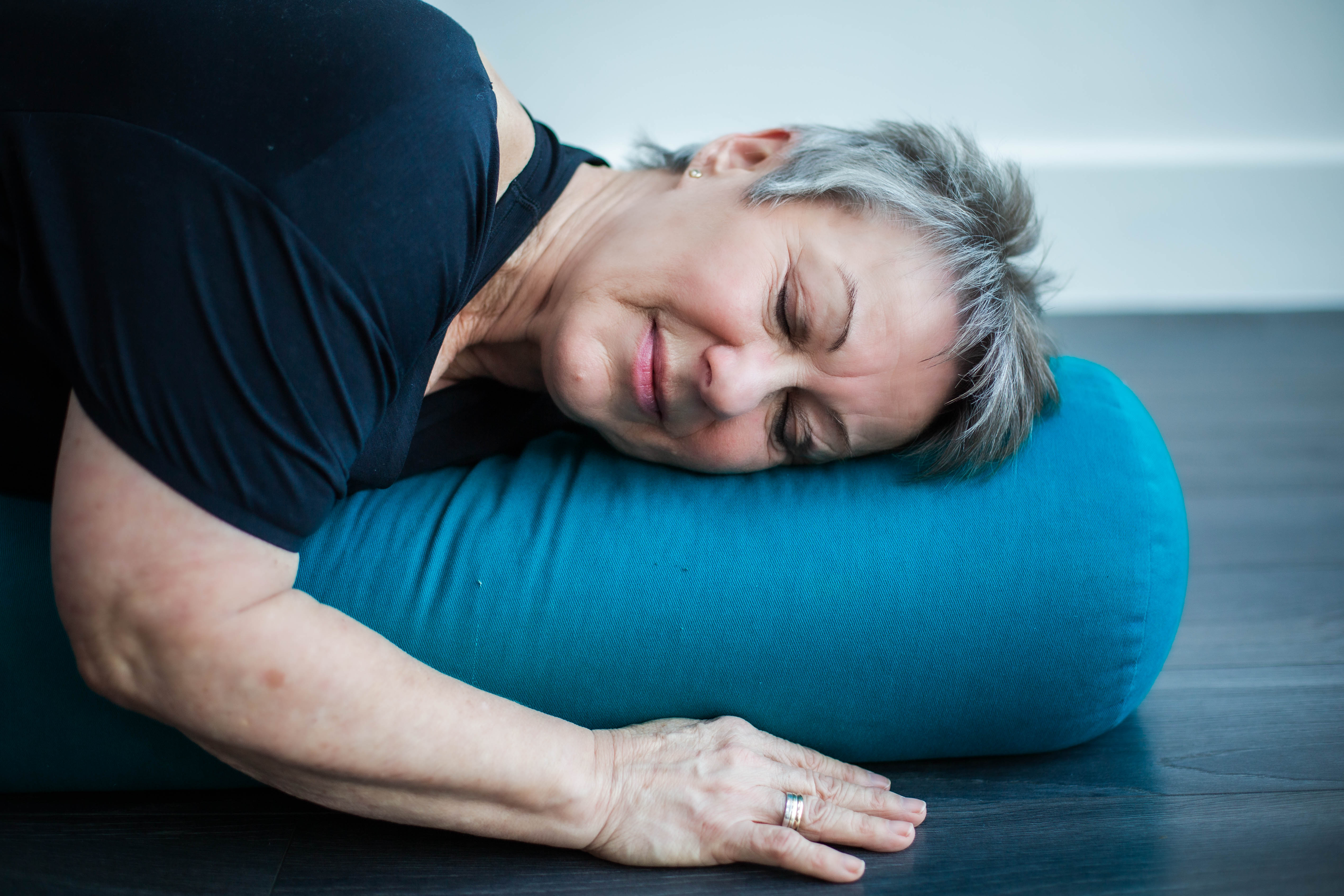 A student resting comfortably on a yoga bolster