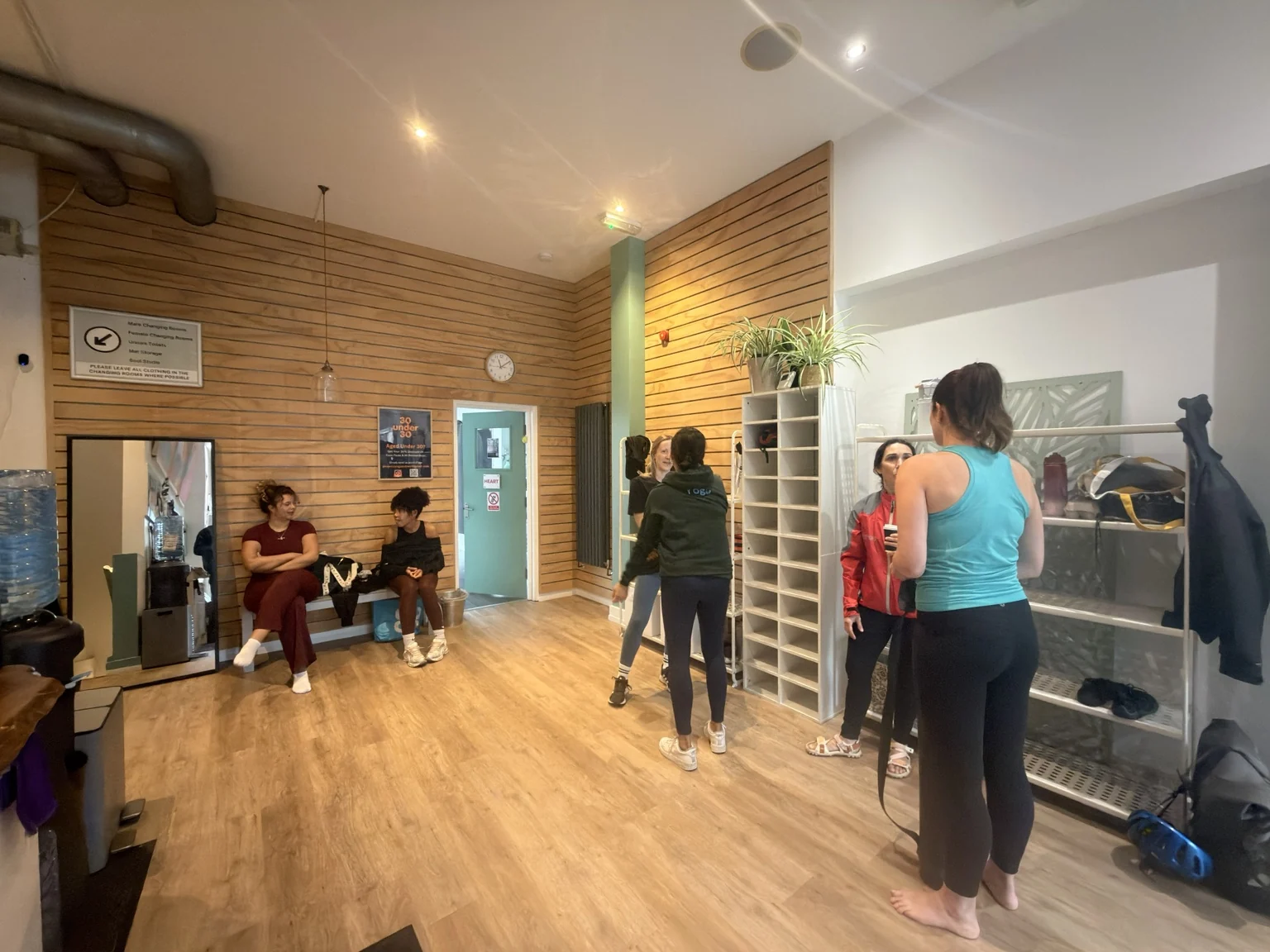 People chatting in the Phoenix front room, beside the timber wall and shelves.